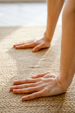 Öne doğru uzanan bir kadın, minderde yoga pozu veriyor. Evde yoga yapan kadın sporcu, ellere odaklan..