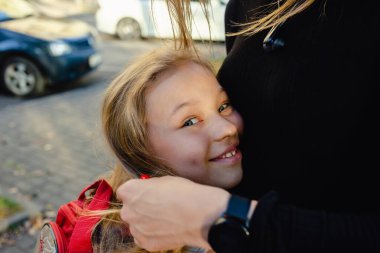 Bir anne, koronavirüs ya da grip salgını sırasında okula giden kızına sarılır. Okula dönelim. Kapat.