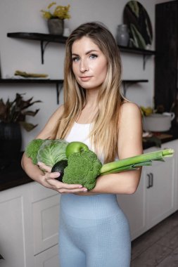 Fitness kadını çiğ yeşil sebze tutar.