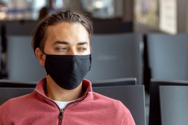 Havaalanında maske takan bir adam. Temalar yeni normal, koronavirüs ve kişisel koruma ile dolaşır.
