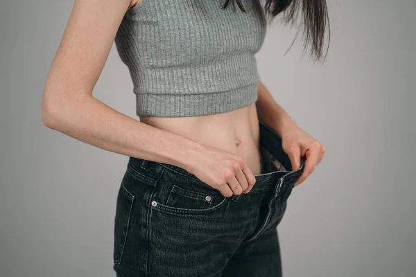 Flickan gick ner mycket i vikt. Anerexia hos en flicka. För stora jeans för en smal tjej — Stockfoto