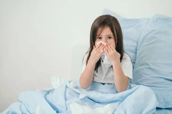 A kislány megfázott. A gyerekek zsebkendőbe tüsszentenek. A gyermek beteg, és otthon kezelik. Szezonális megfázás gyermekeknél — Stock Fotó