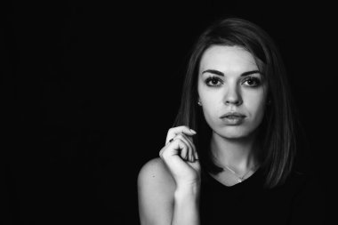 Siyah arka planda ciddi bir kız. Kız elleriyle yüzünü kapatıyor. Kadının ciddi sorunları var. Siyah beyaz bir kızın yakın plan portresi.