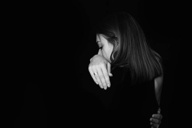 Modern insanda depresyon. Kız arkası siyah arkaplana dönük duruyor. Üzgün bir kızın siyah beyaz portresi