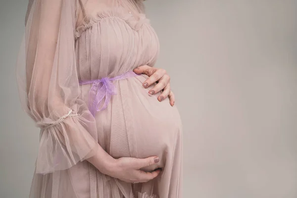 Hamile bir kız karnını tutuyor. Genç bir anne bir çocuğun doğmasını bekliyor. Kadın nazikçe bebeğinin karnına sarılıyor. — Stok fotoğraf