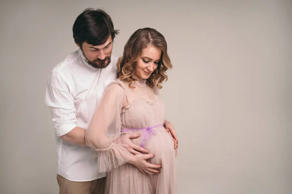 Um homem feliz abraça uma mulher grávida. Um par de abraços amorosos. Homem e mulher estão esperando o nascimento de uma criança — Fotografia de Stock