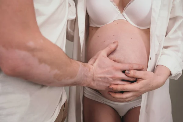 Szczęśliwy mężczyzna stoi obok swojej ciężarnej dziewczyny. Kochający rodzice czekają na narodziny dziecka. Mąż przytula swoje ciężarne żony żołądek — Zdjęcie stockowe