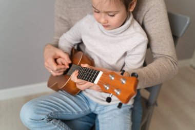Babam kızıyla gitar çalar. Çocuk bir öğretmenle müzik aleti çalmayı öğreniyor. Çocuklu bir babanın müzikal düeti.