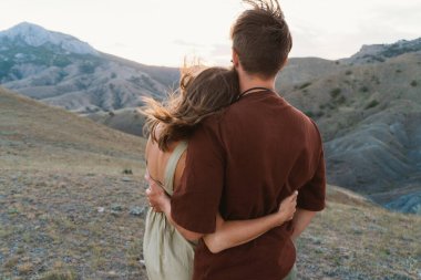 Sevgililer gün batımını severler. Adam ve kız ayaktalar ve sarılıyorlar. Dağın tepesinde romantik bir randevu. Sevgililer Günü aşıklar tarafından kutlanır.
