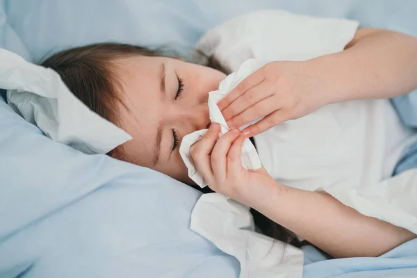 A kislány megfázott. A gyerekek zsebkendőbe tüsszentenek. A gyermek beteg, és otthon kezelik. Szezonális megfázás gyermekeknél — Stock Fotó