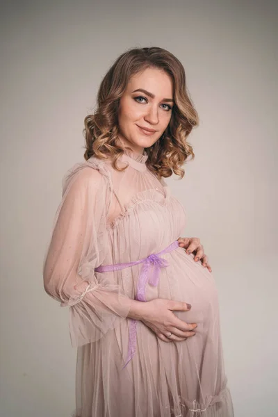 Eine Schwangere hält ihren Bauch. Eine junge Mutter erwartet die Geburt eines Kindes. Frau umarmt ihr Baby sanft im Bauch — Stockfoto