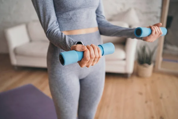 Doing sports at home online. Sports girl doing exercises. A girl in a gray tracksuit goes in for sports. Young woman exercising at home in a living room