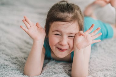 Çocuk oyun oynuyor ve gülüyor. Mavi takım elbiseli küçük bir kızın portresi. Bebek saklambaç oynuyor