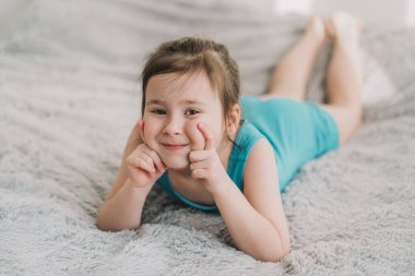 Güzel küçük bir kızın portresi. Çocuk yatak odasındaki yatakta yatıyor.