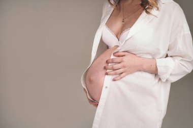 Hamile bir kadının karnında gerilme izleri var. Kız bir çocuk bekliyor. Hamile genç anne karnını tutuyor.