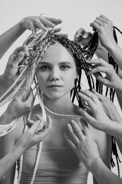Black and white portrait of a beautiful girl. Lots of hands around a womans face. Creative portrait of the original woman