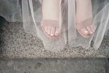 Güzel pedikürlü bacaklar. Yumuşak yaz pedikürü. Yürümek için güzel sandaletler. Pedikür hakkında bir metin için yer