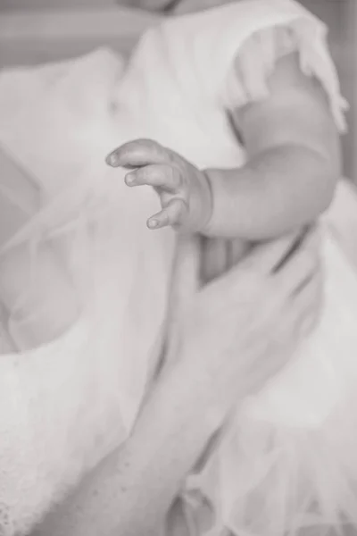 De moeder houdt het kind in haar armen. Zwart-wit frame van de kinderpen. Close-up van de handen van de kinderen en moeders. — Stockfoto