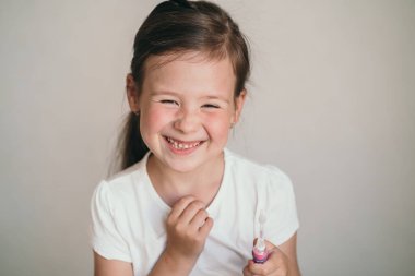 Çocuk dişlerini bir fırçayla fırçalar. Küçük kız mutlu bir şekilde yıkanır ve dişleriyle ilgilenir. Pembe diş fırçası. Çocuklarda ağız temizliği.