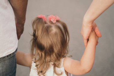 Ebeveynler bebeklerin ellerini tutar. Çocuk anne ve babasıyla eğleniyor. Bebeğin ellerine ve annenin ellerine yakın çekim. Mutlu ve tasasız bir çocukluk.