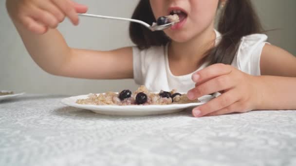A criança é caprichosa e se recusa a comer. A menina recusa um prato de mingau de cereal. A menina empurra o mingau para longe de si mesma. Um close-up das mãos das crianças empurrando o mingau de cereal. — Vídeo de Stock