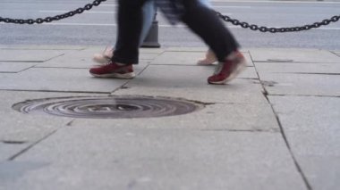 İnsanlar caddede yürüyorlar. Yoldan geçenlerin bacakları yakındır. Bir kalabalık caddede yürüyor. İnsanlar yazın yağmurlu şehirde yürürler.
