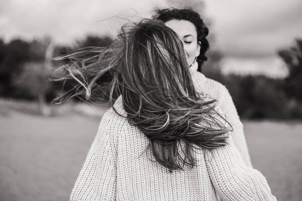 Lifestyle black and white photo of two girl. Free women enjoy life. The wind blows the thick dark hair of the two friends. High quality photo