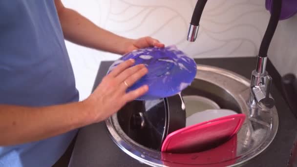 Un uomo lava i piatti con una spugna. Una persona lava via il detergente con acqua dai piatti. Primo piano della mano dell'uomo che pulisce i piatti. L'uomo pulisce i piatti dopo se stesso — Video Stock