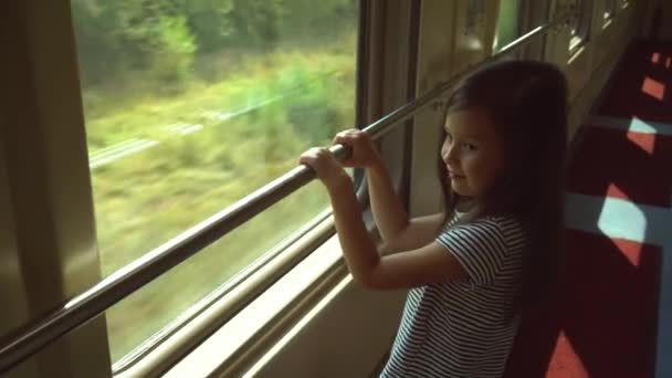 Il bambino sale sul treno e guarda fuori dal finestrino. Lungo viaggio in treno. La ragazza guarda attentamente fuori dal finestrino del treno — Video Stock