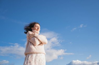 Sıcak kazaklı romantik bir kız kendine sarılıyor. Esmer kız rüyasında gözlerini kapadı. Bir kadın bulutlarla gökyüzüne karşı duruyor..