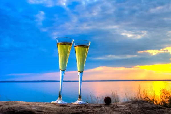 Two glasses of champagne white wine standing on a log — Stock Photo, Image