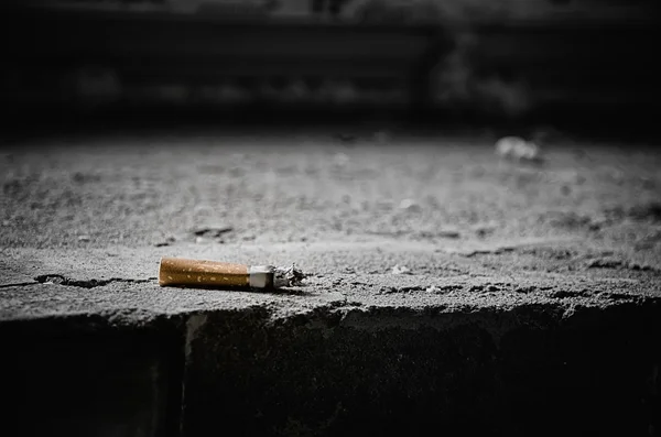 Bunda de cigarro nos degraus de pedra . — Fotografia de Stock