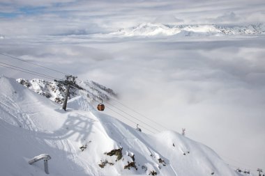 Kar bulutların üzerinden yükselir. Kafkasya sallanıyor. Beyaz dağlar ve mavi gökyüzü.