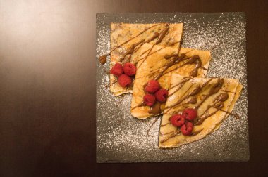 Çikolata ve ahududu dolu krepler ve kare bir tabakta jöleli şeker.