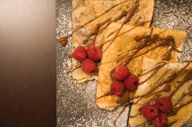 Çikolata ve ahududu dolu krepler ve kare bir tabakta jöleli şeker.