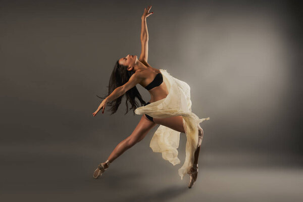 Ballet dancer with black lingerie and gauze covering her doing dance pose