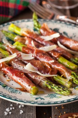 Parma ham plaka üzerinde yeşil kuşkonmaz sarılı