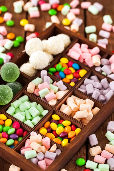 Mix of candies and sweets in wooden box — Stock Photo, Image