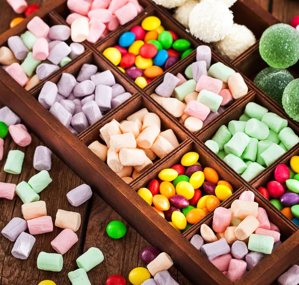 Mix of candies and sweets in wooden box — Stock Photo, Image