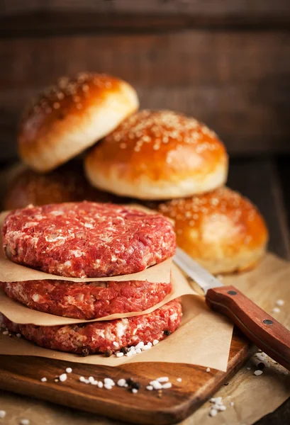 Raw ground beef meat steak cutlets and burger buns — Stock Photo, Image