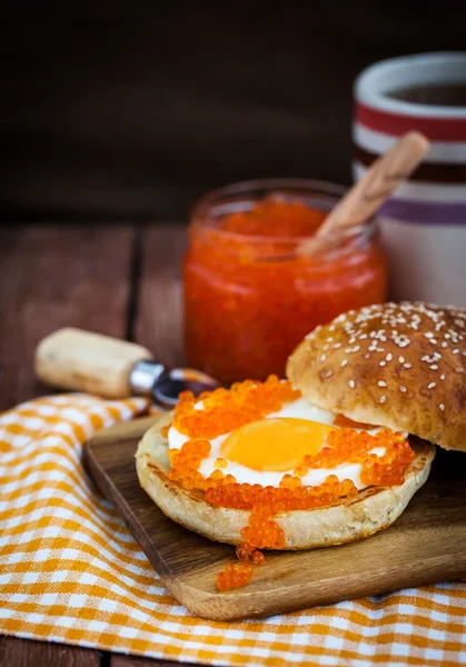 Fried egg with red caviar on a bun — Stock Photo, Image