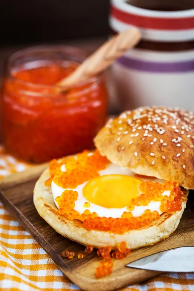 Fried egg with red caviar on a bun — Stock Photo, Image