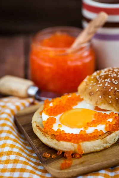 Fried egg with red caviar on a bun — Stock Photo, Image