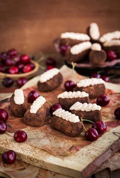 Bolos de bolas de rum de chocolate decorados com creme e cereja fresca — Fotografia de Stock