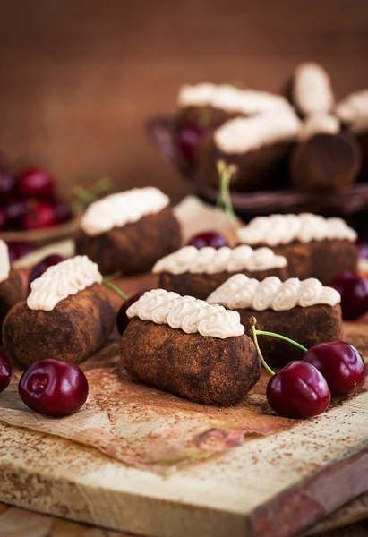 Chocolate rum balls cakes decorated with cream and fresh cherry — Stock Photo, Image