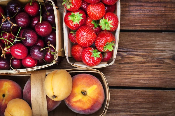 Verse rijpe zomer bessen en fruit in manden — Stockfoto