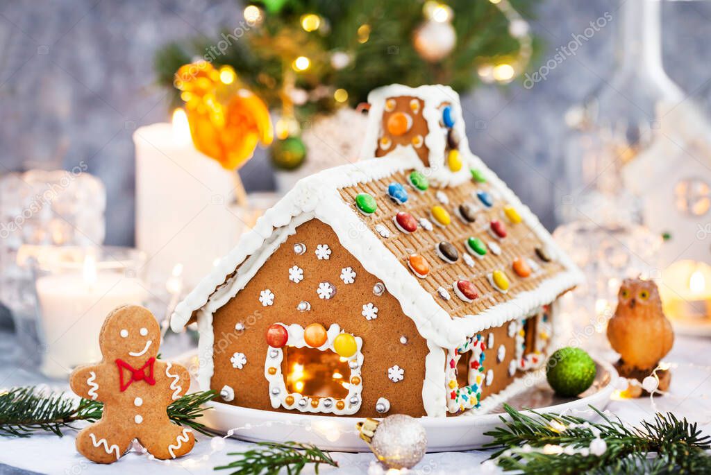 Homemade Christmas gingerbread house with holiday   decorations, candles and lanterns on  background