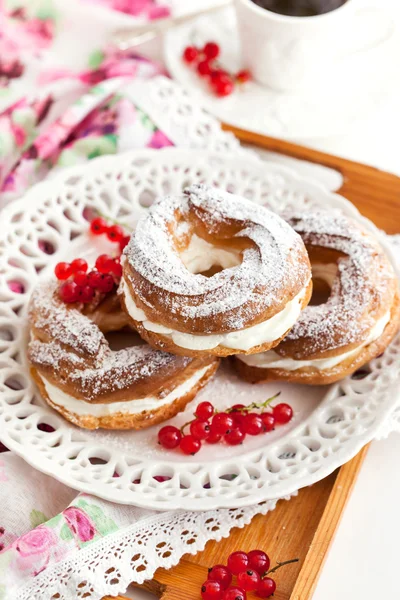 Cream puff rings decorated with fresh red currant