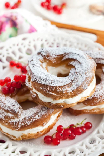 Cream puff rings decorated with fresh red currant — Stock Photo, Image