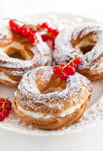 Cream puff rings decorated with fresh red currant — Stock Photo, Image